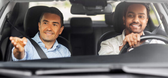 Jeune homme apprenant à conduire une voiture avec son moniteur d'auto-école